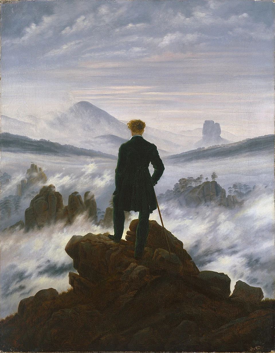 A lone hiker facing a vast mountain landscape